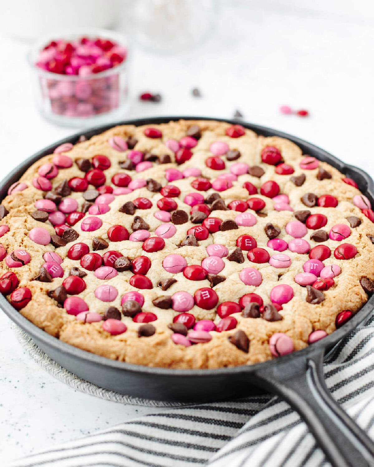 A cast iron skillet with a baked chocolate chip skillet cookie ready to serve.