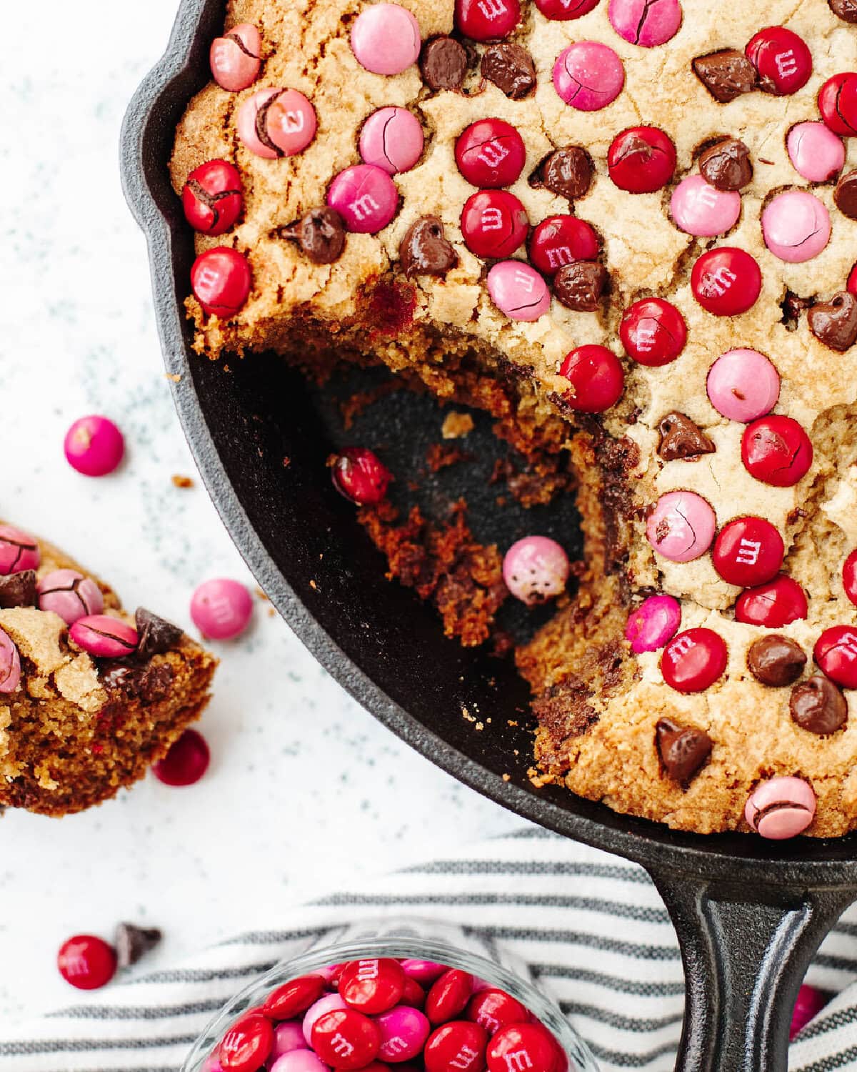 A scoop of cookie taken out of a baked chocolate chip cookie skillet.