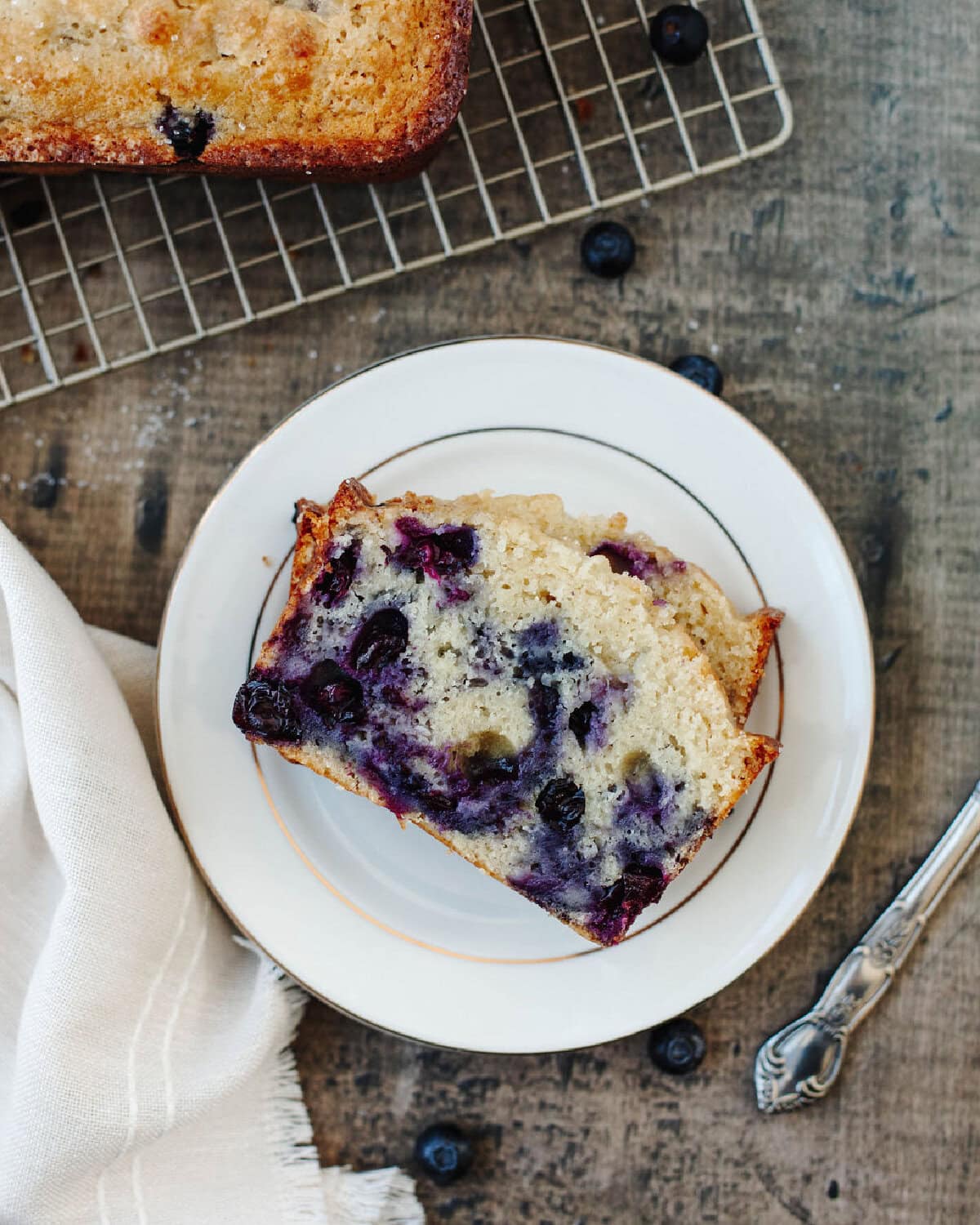 Slices of blueberry muffin quick bread on a white serving plate.
