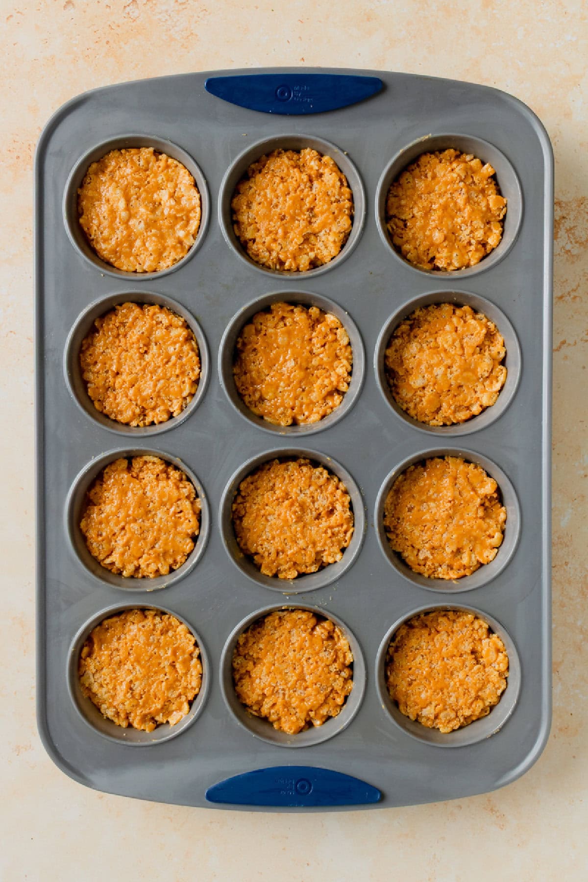 Peanut butter rice krispie mixture pressed into muffin tin to form cereal cups.