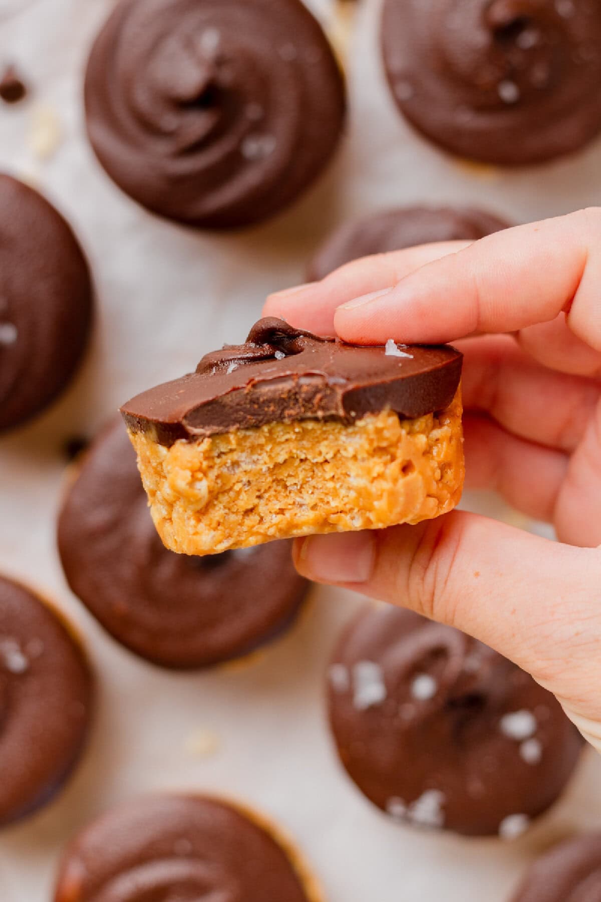 Chocolate peanut butter rice krispie cup with a bite taken out showing the crunchy cereal and peanut butter center.