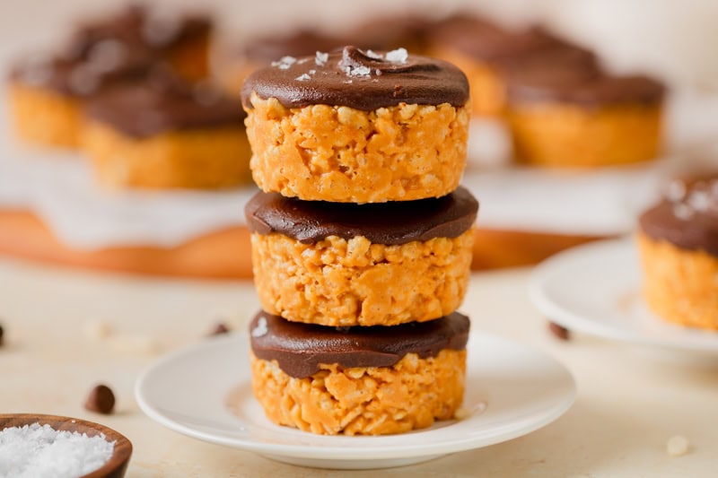 A stack of chocolate peanut butter rice krispy cups on a white dessert plate.