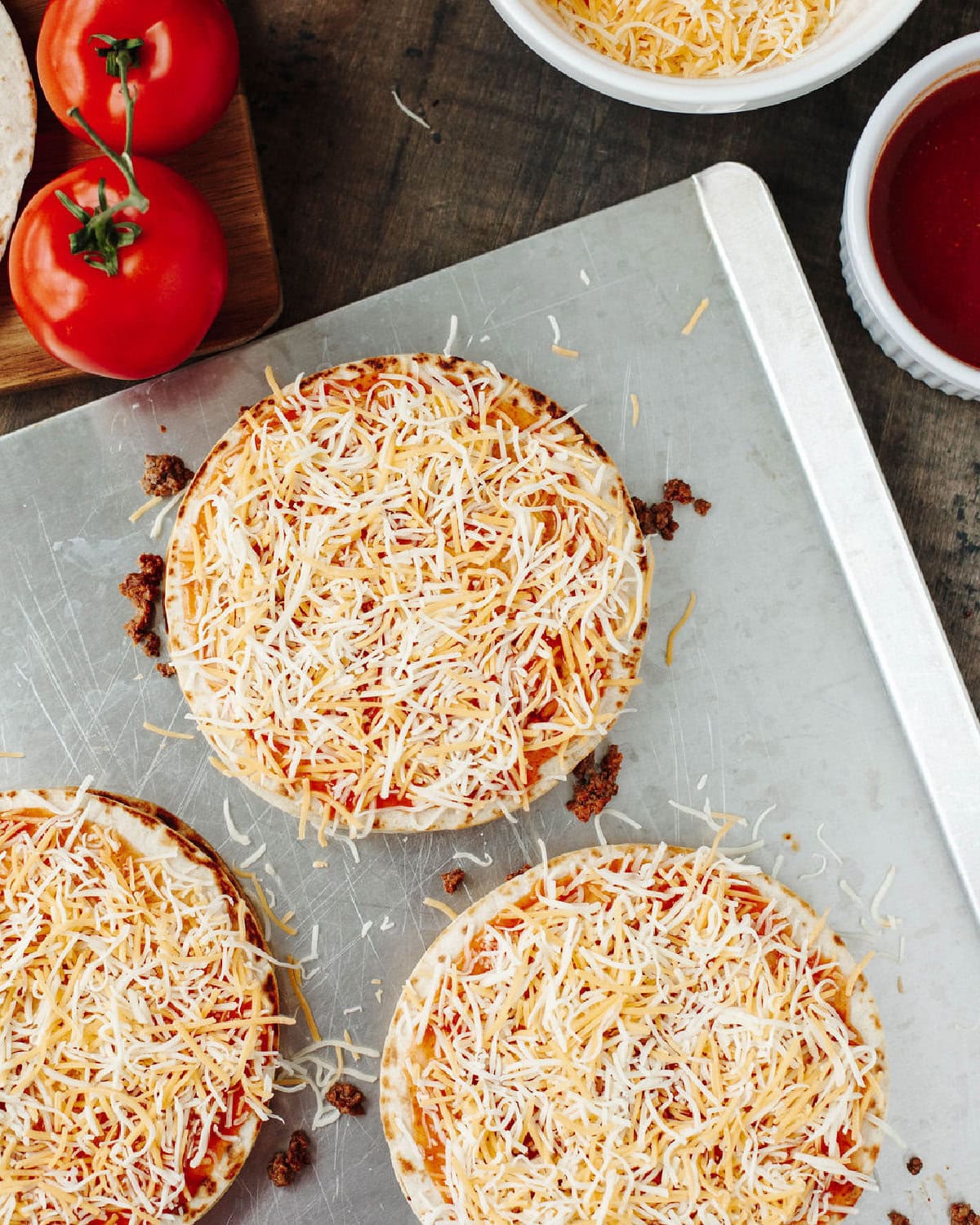 Shredded cheese on top of layered Mexican pizzas.