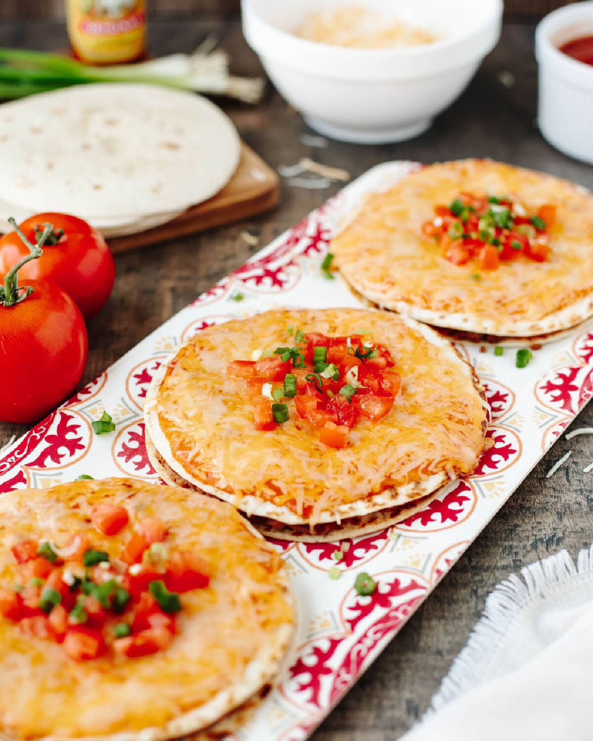 Copycat Mexican pizzas on a fiesta themed serving tray ready to serve.
