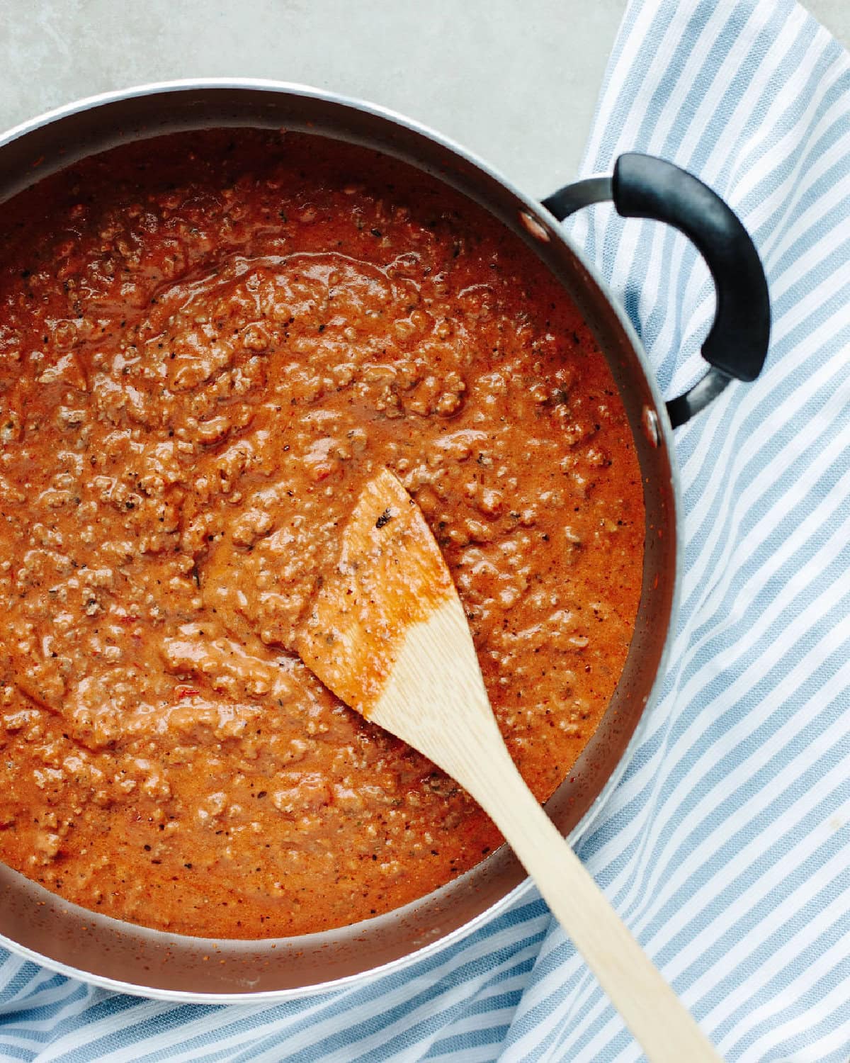 Spaghetti sauce and cream cheese stirred into cooked ground beef seasoned with Italian seasoning in a skillet.