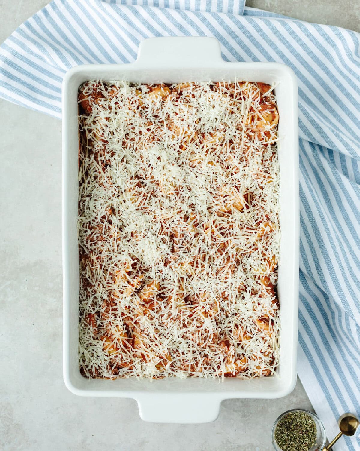 Shredded mozzarella cheese and Parmesan cheese spread on top of a baked tortellini casserole.