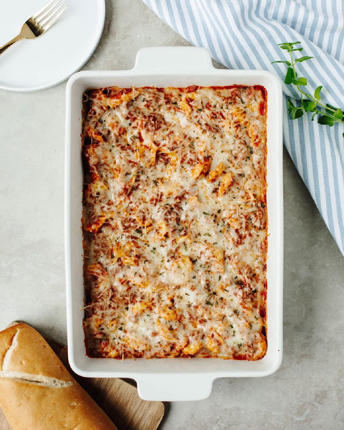Baked tortellini with cream cheese in a white baking pan ready to serve.
