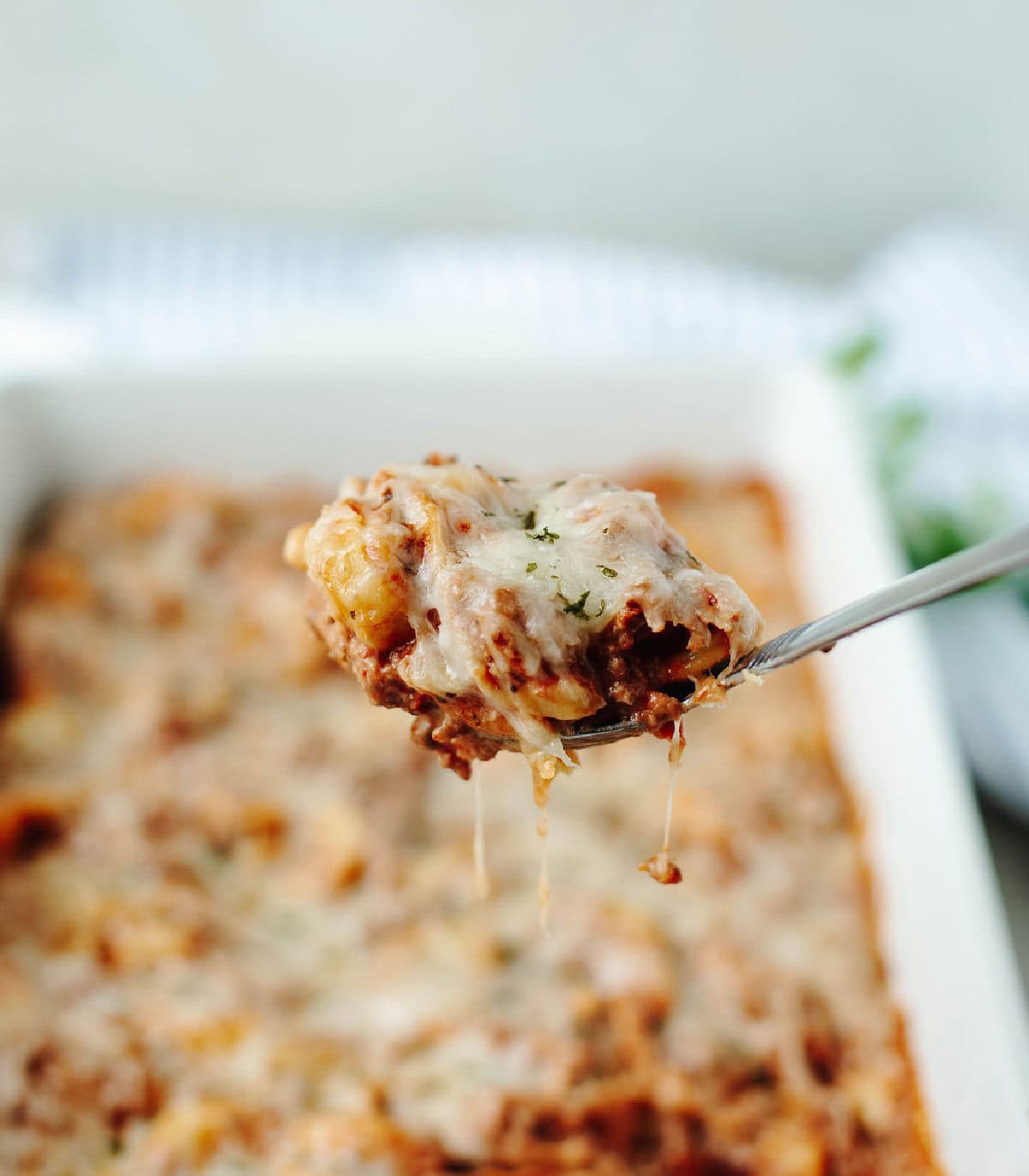 A spoon holding a bite of creamy baked tortellini.