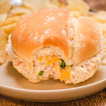 A crockpot crack chicken sandwich served on a plate with chips.