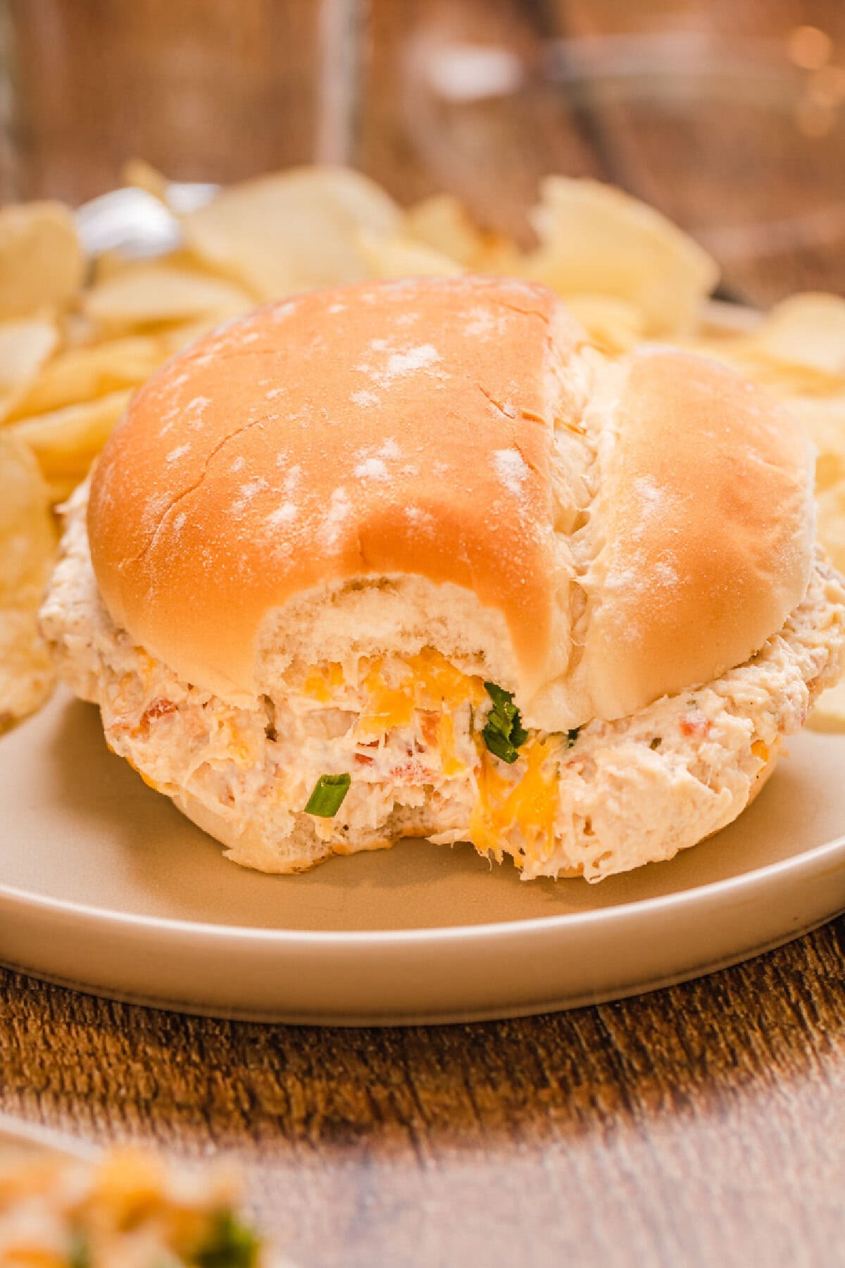 A crockpot crack chicken sandwich served on a plate with chips.