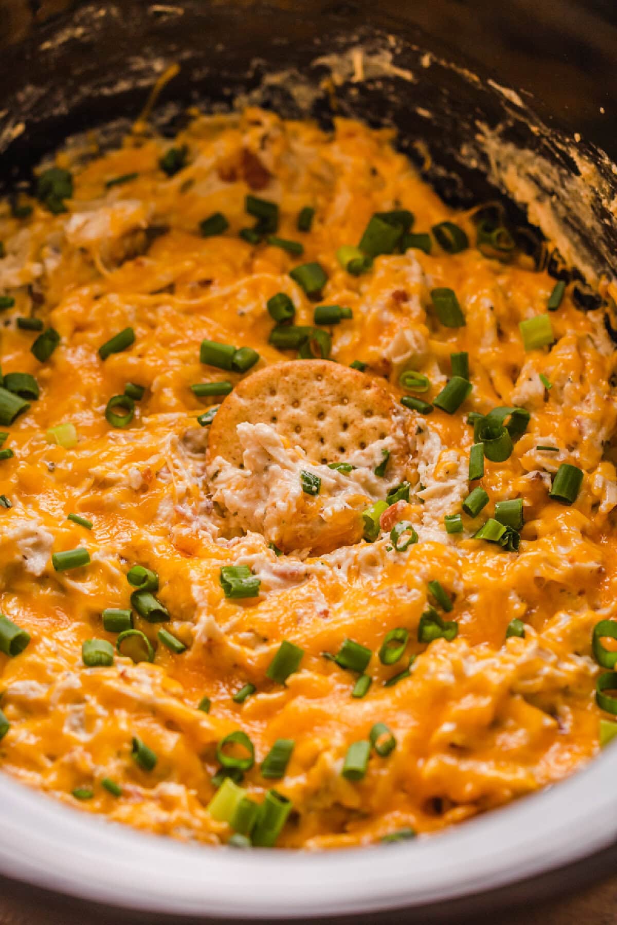 Cheesy crack chicken made in the crockpot and served with crackers and green onions.