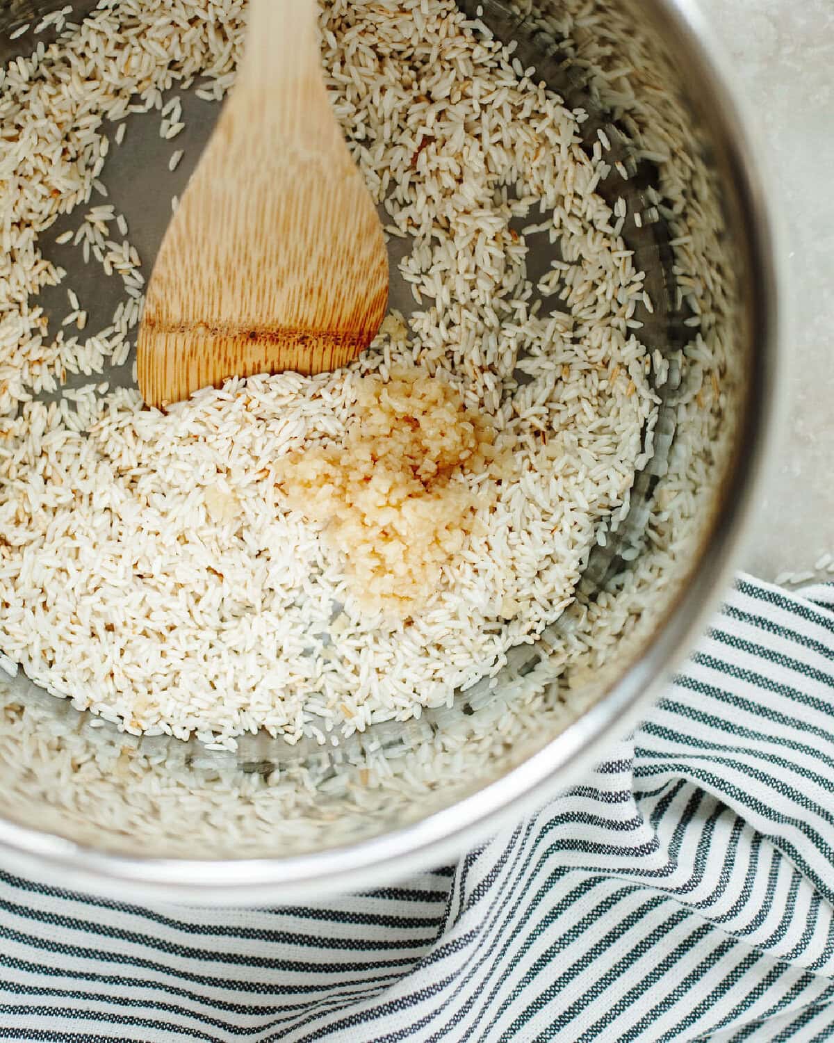 Minced garlic added to rice in a pressure cooker liner.