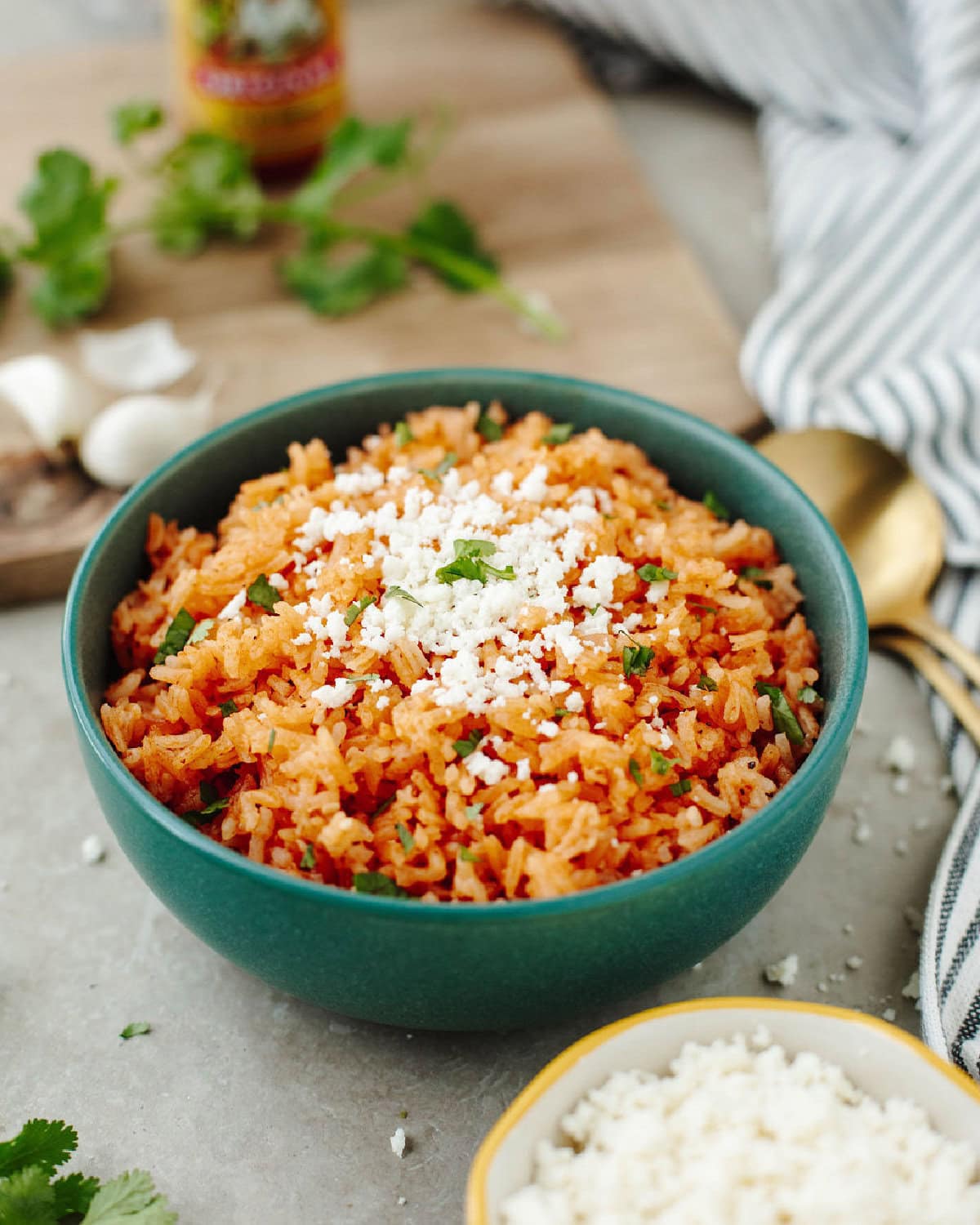 A serving bowl of Mexican rice with grated fresh cheese on top.