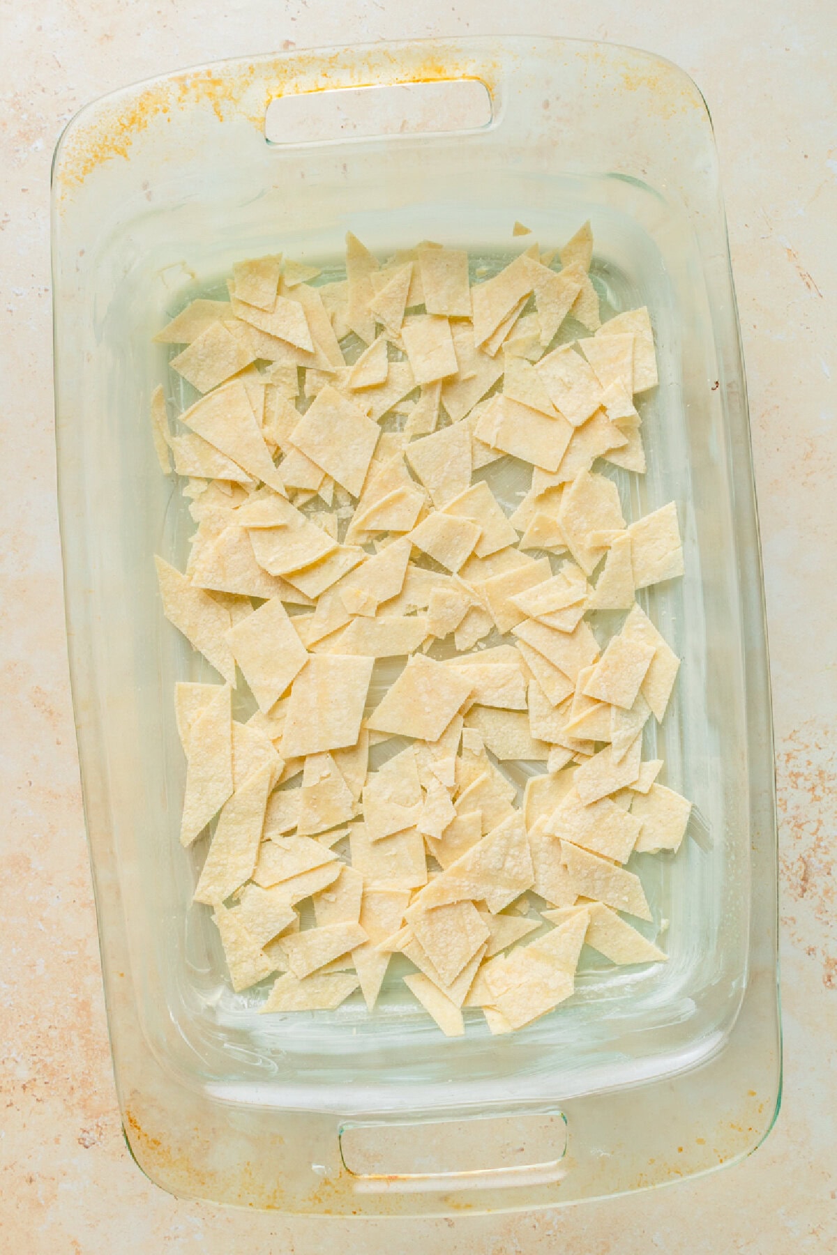 Chopped corn tortillas layering the bottom of a 9x13 baking pan.