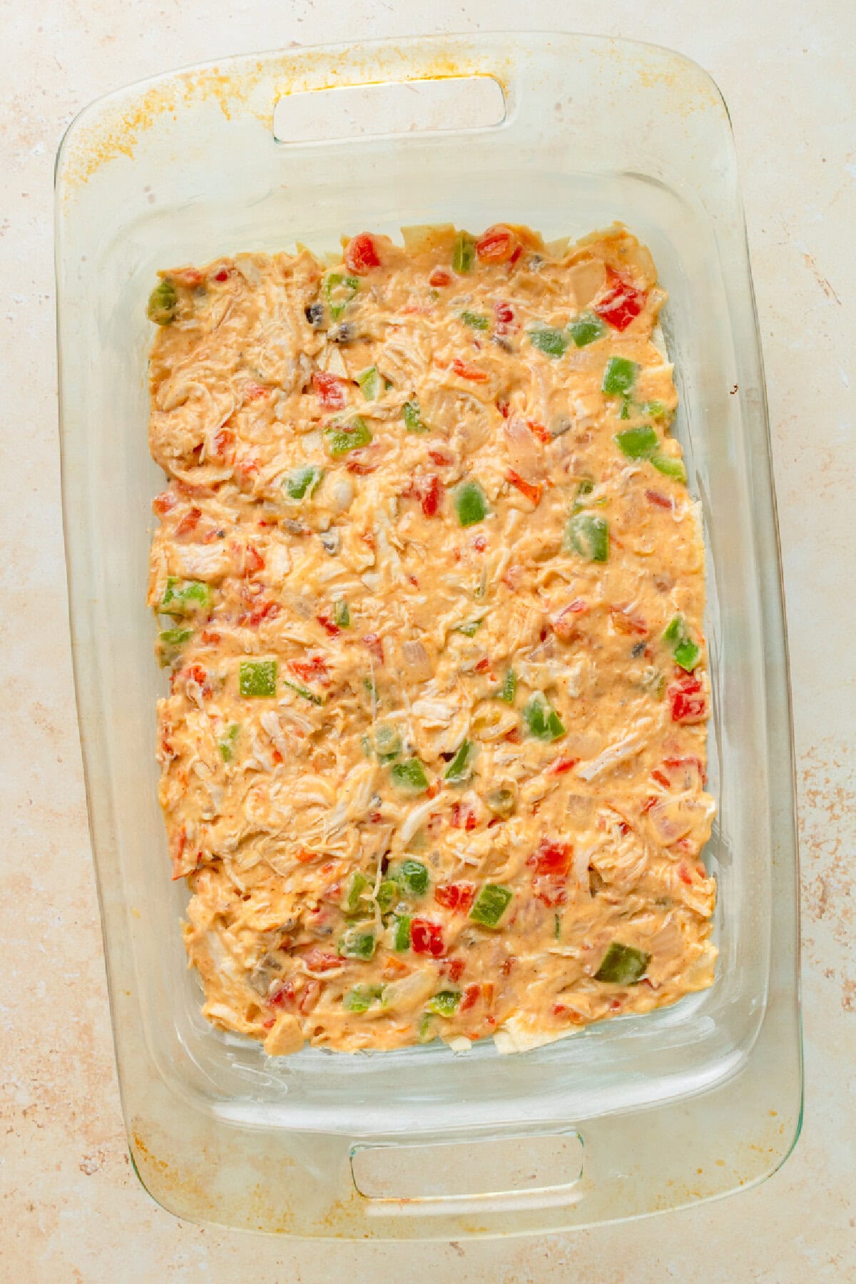 Creamy chicken mixture spread into an even layer in a 9x13 baking pan.