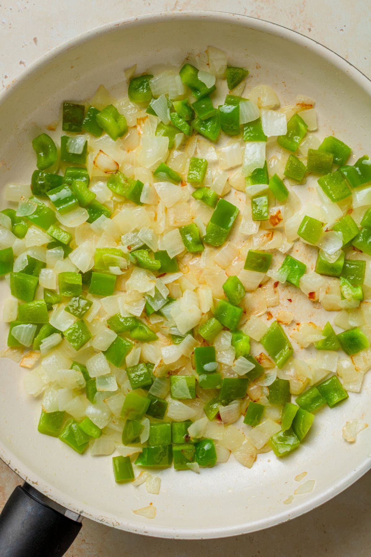 Sauteed green peppers and onions in a skillet.