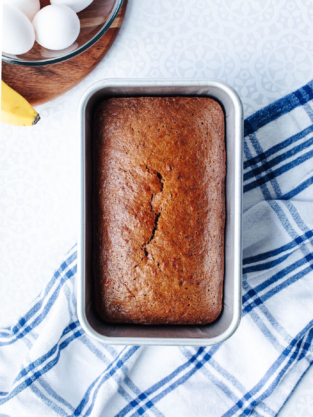 Freshly baked banana bread with mayo cooling in a loaf pan.