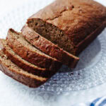 Baked banana bread with mayo sliced on a glass serving platter.