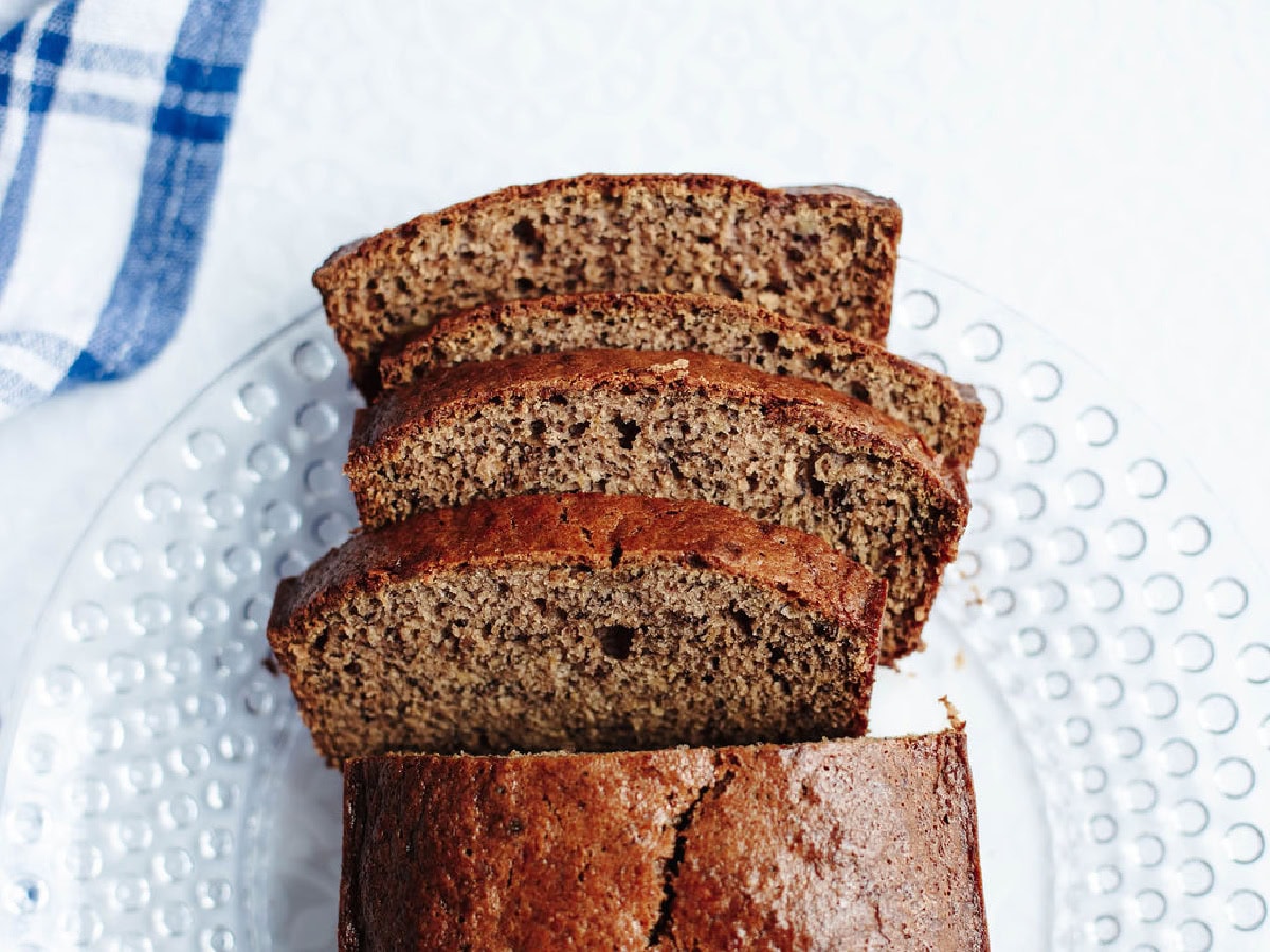 Sliced mayonnaise banana bread on a glass serving tray.