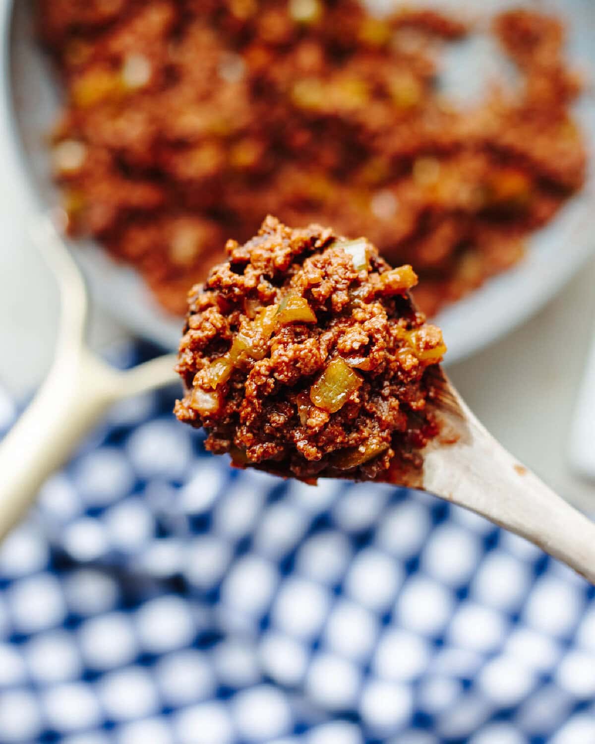 A wood spoon with a scoop of sloppy joes ready to serve.