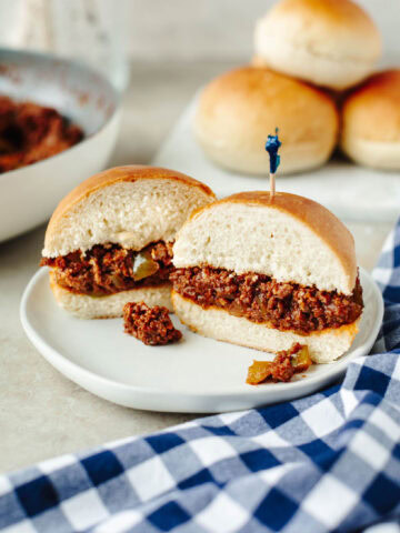 Sloppy joes served on buttery bread machine rolls on a white plate.