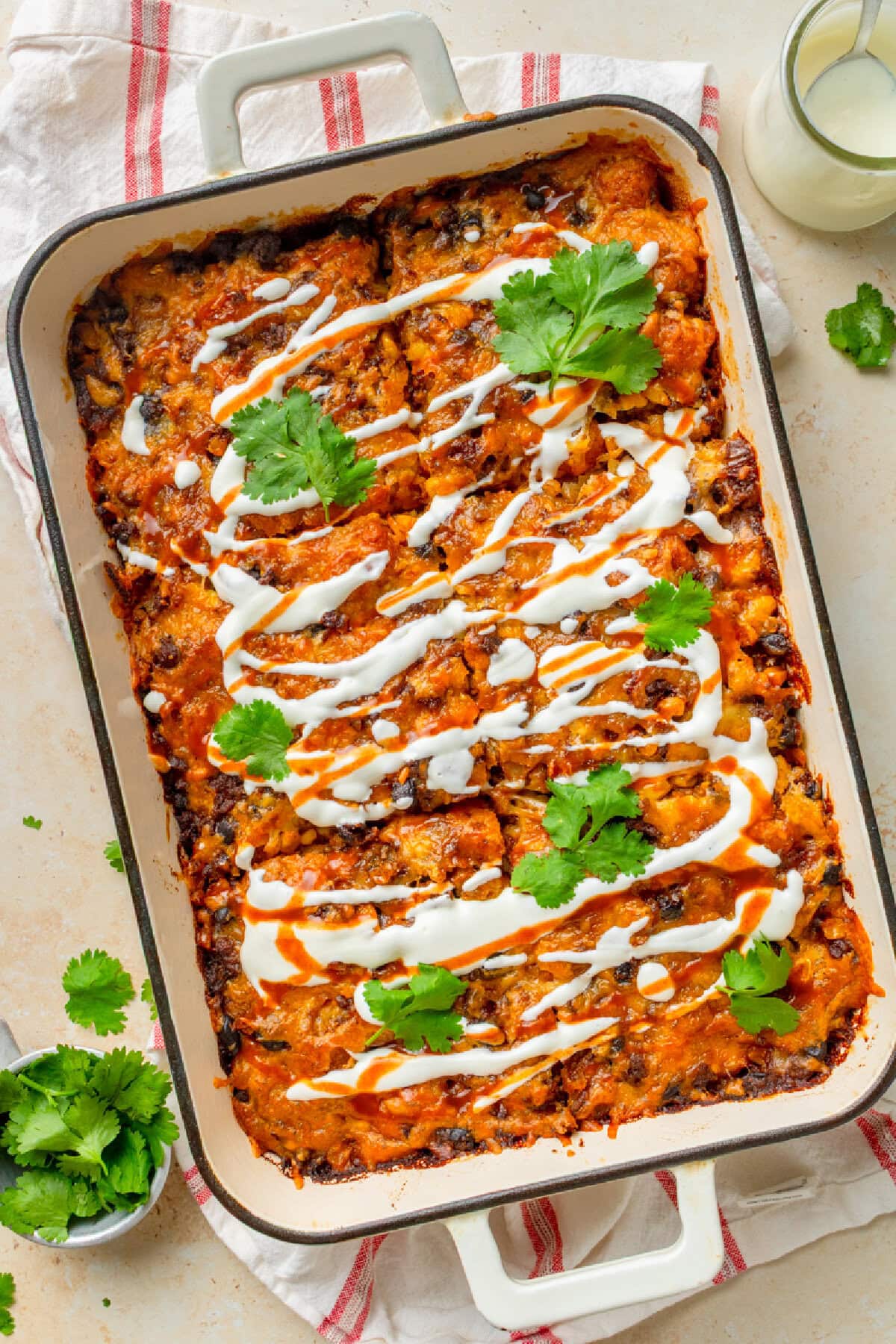 Baked taco tater tot bake in a casserole pan with sour cream and cilantro.