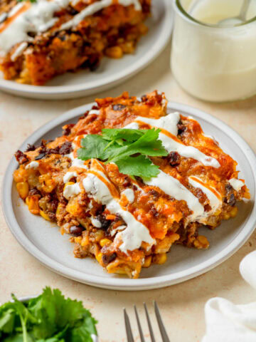A piece of taco tater tot bake on a plate with sour cream and cilantro.
