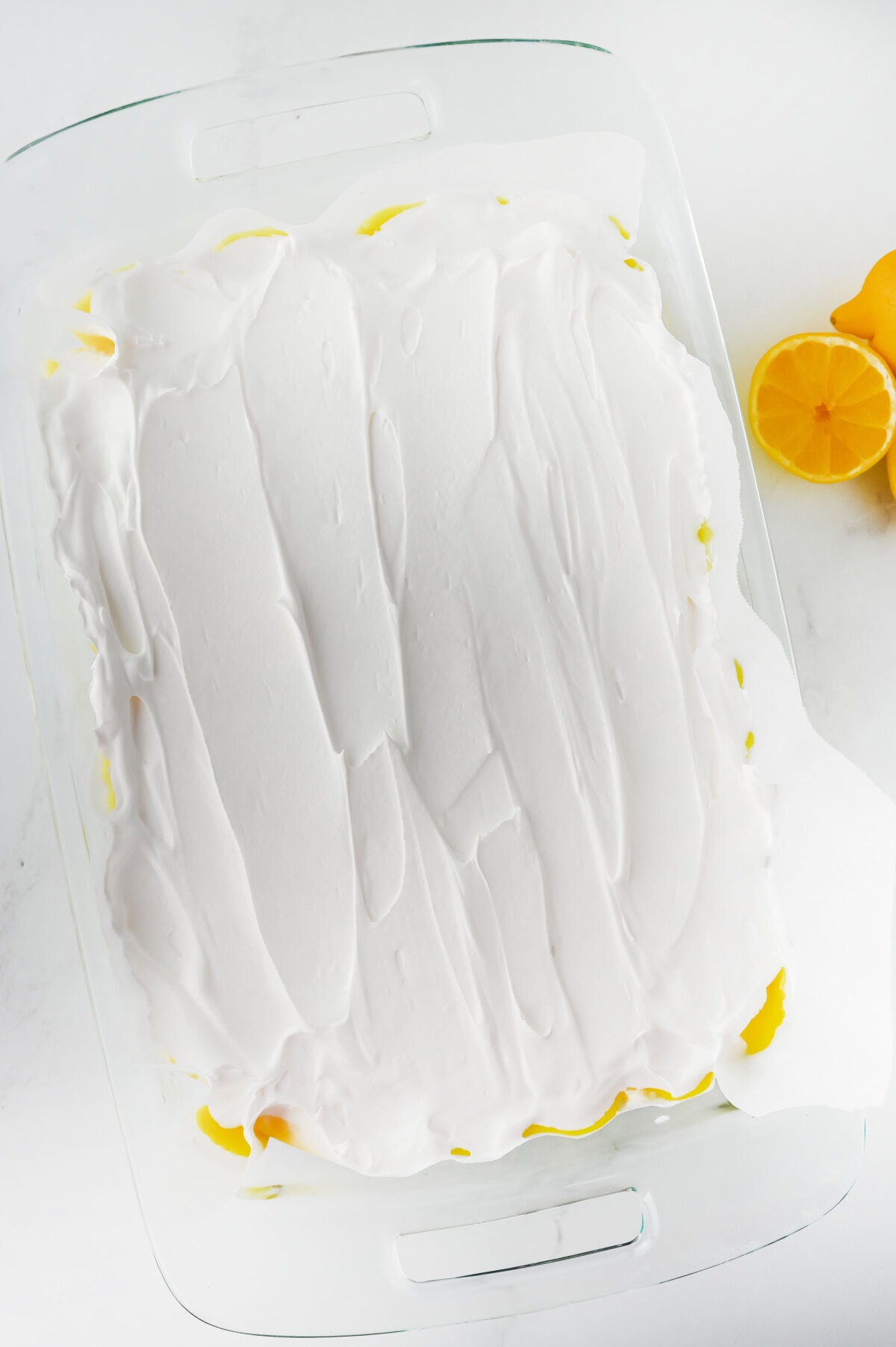 Cool whip spread evenly on top of a lemon dessert in a 9x13 baking dish.