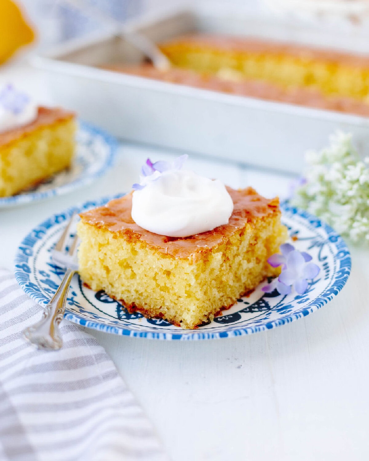 A served slice of lemon poke cake on a floral plate.
