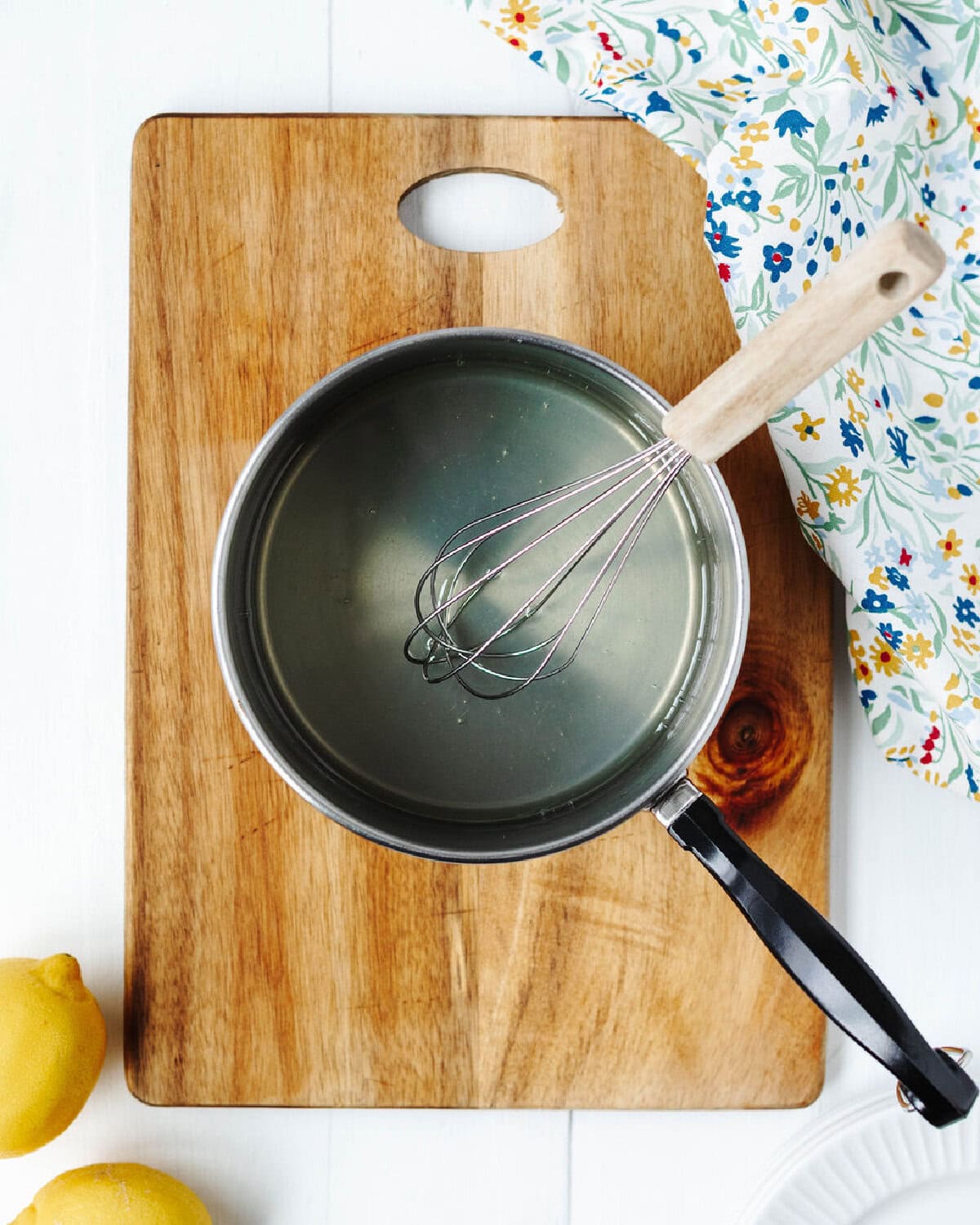 A lemon glaze made in a saucepan with a whisk.