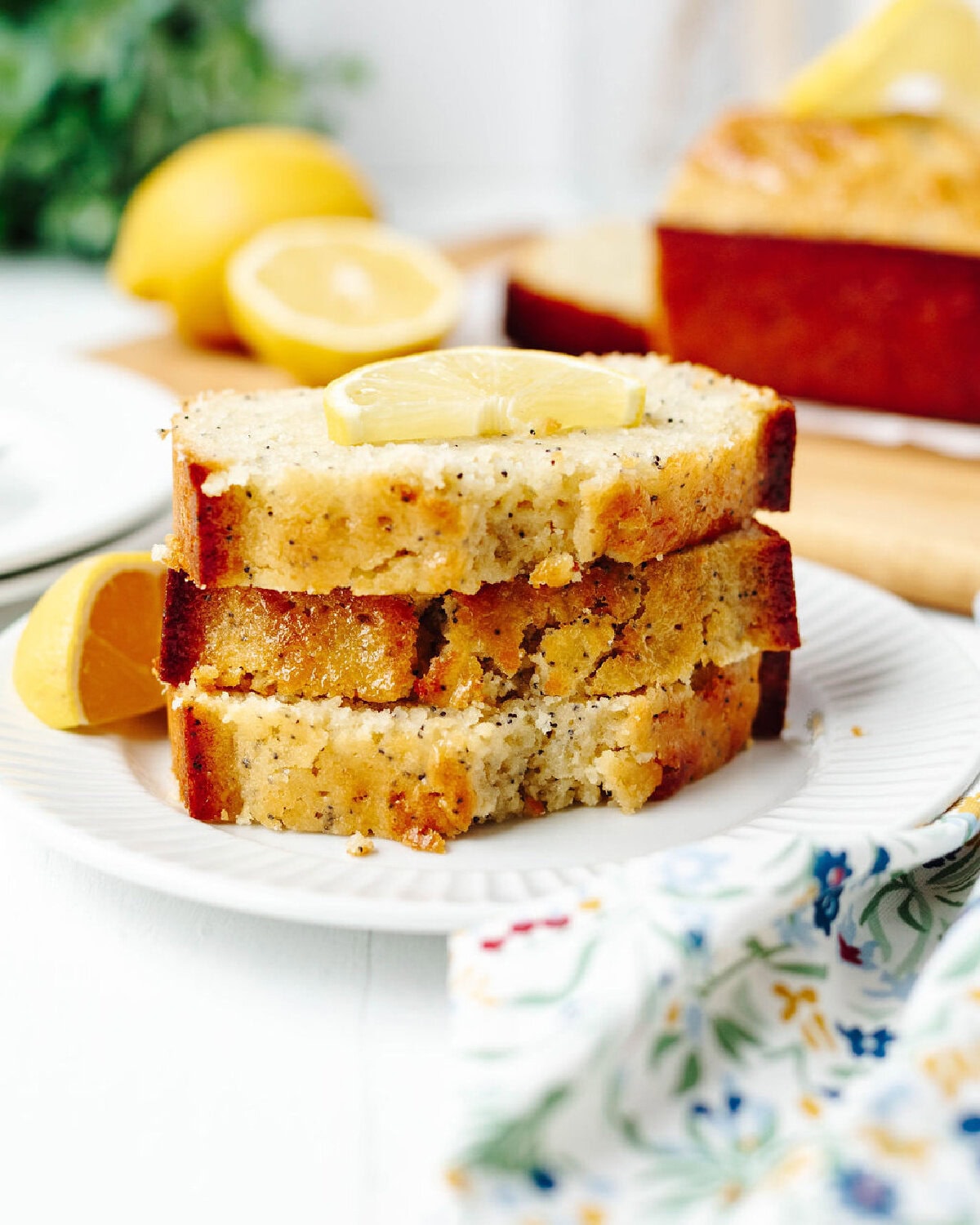 moist lemon poppyseed bread slices with lemon glaze on a white plate.