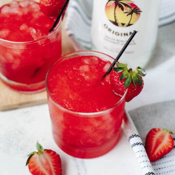 Liquid Skittles Cocktails in glasses with a strawberry on the rim.