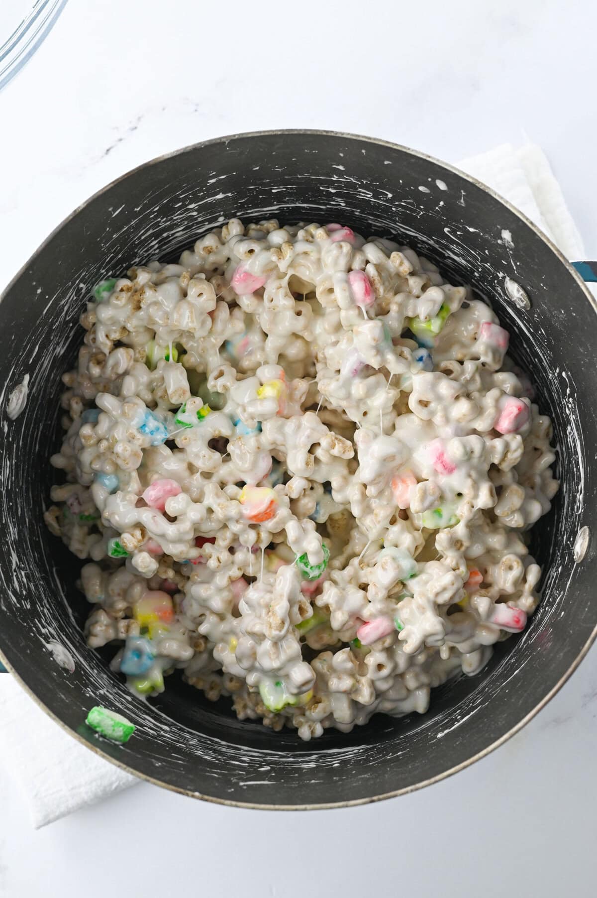 Melted marshmallows coating lucky charm cereal in a pot.