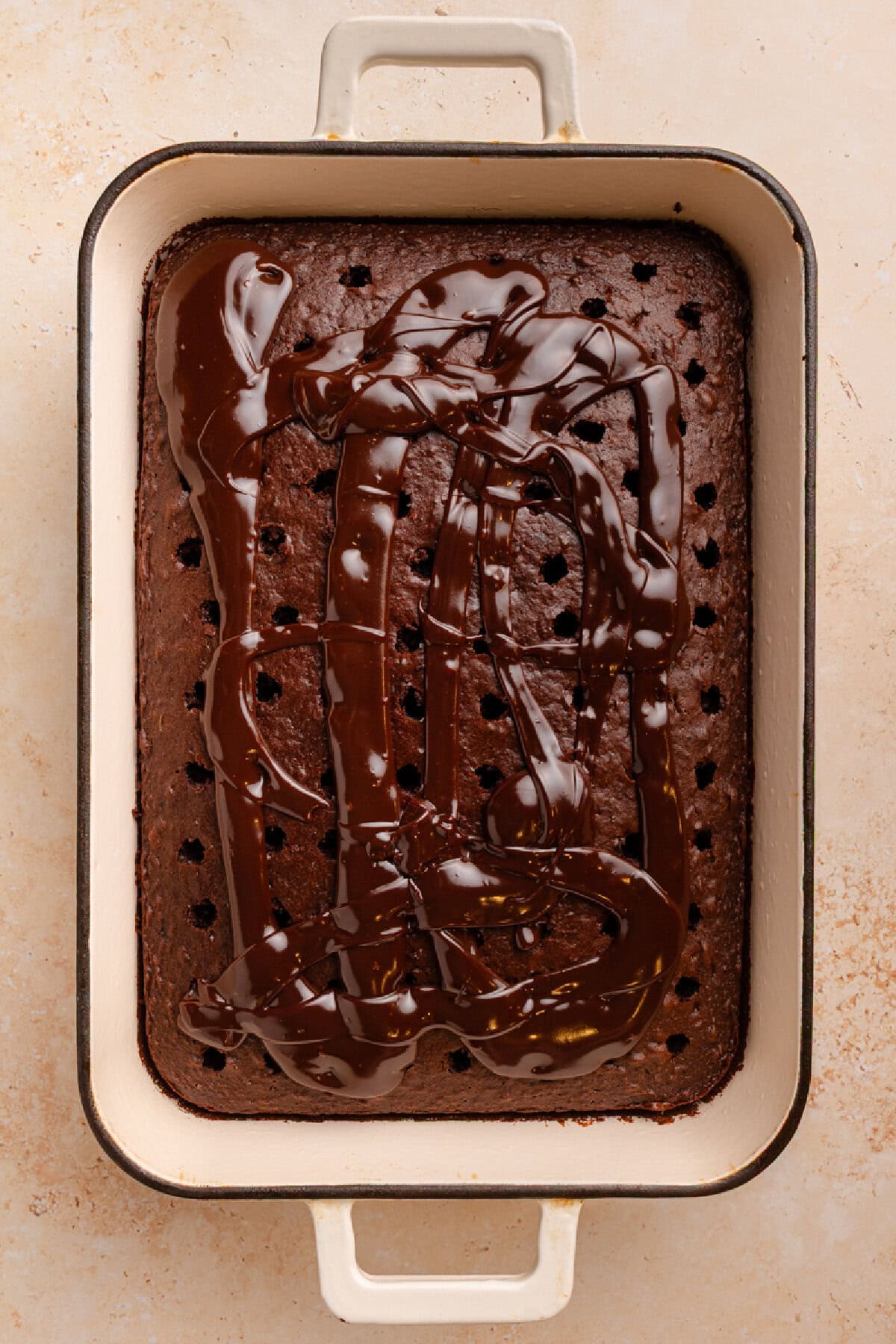 Hot fudge spread on top of poked holes in a chocolate cake.