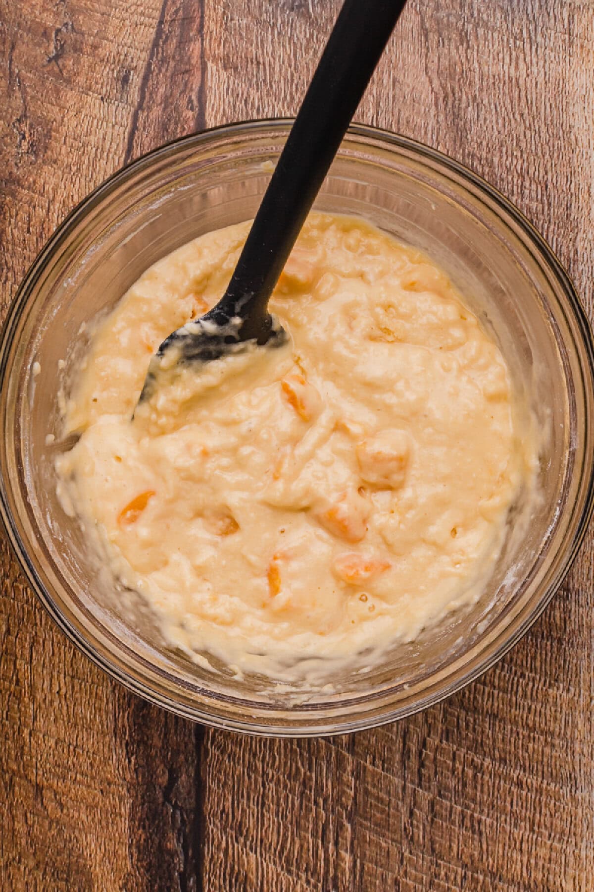 Peaches folded into quick bread batter in a glass mixing bowl.