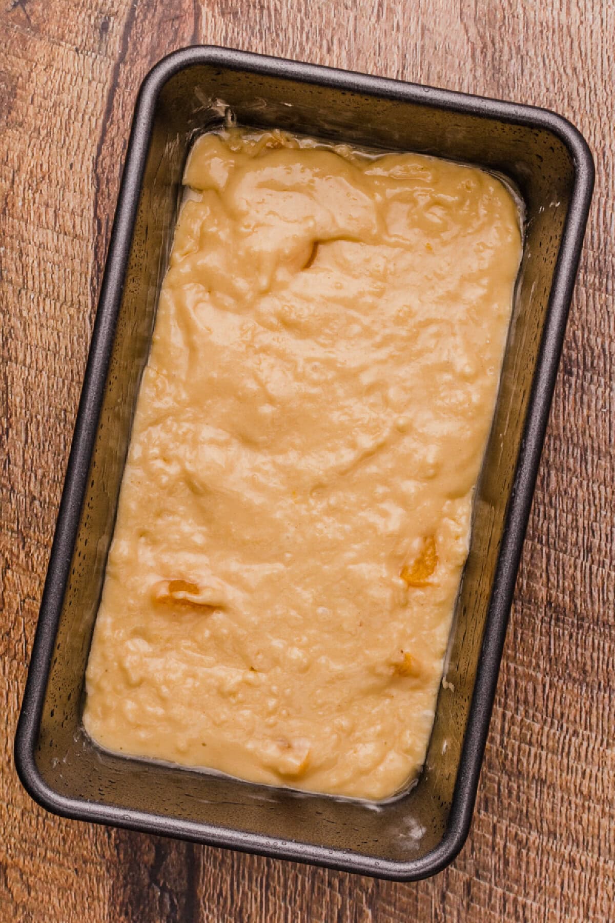 Quick bread batter spread evenly into a prepared loaf pan.