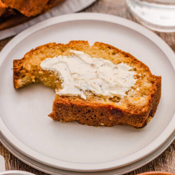 Buttered slice of peach bread on a white plate.