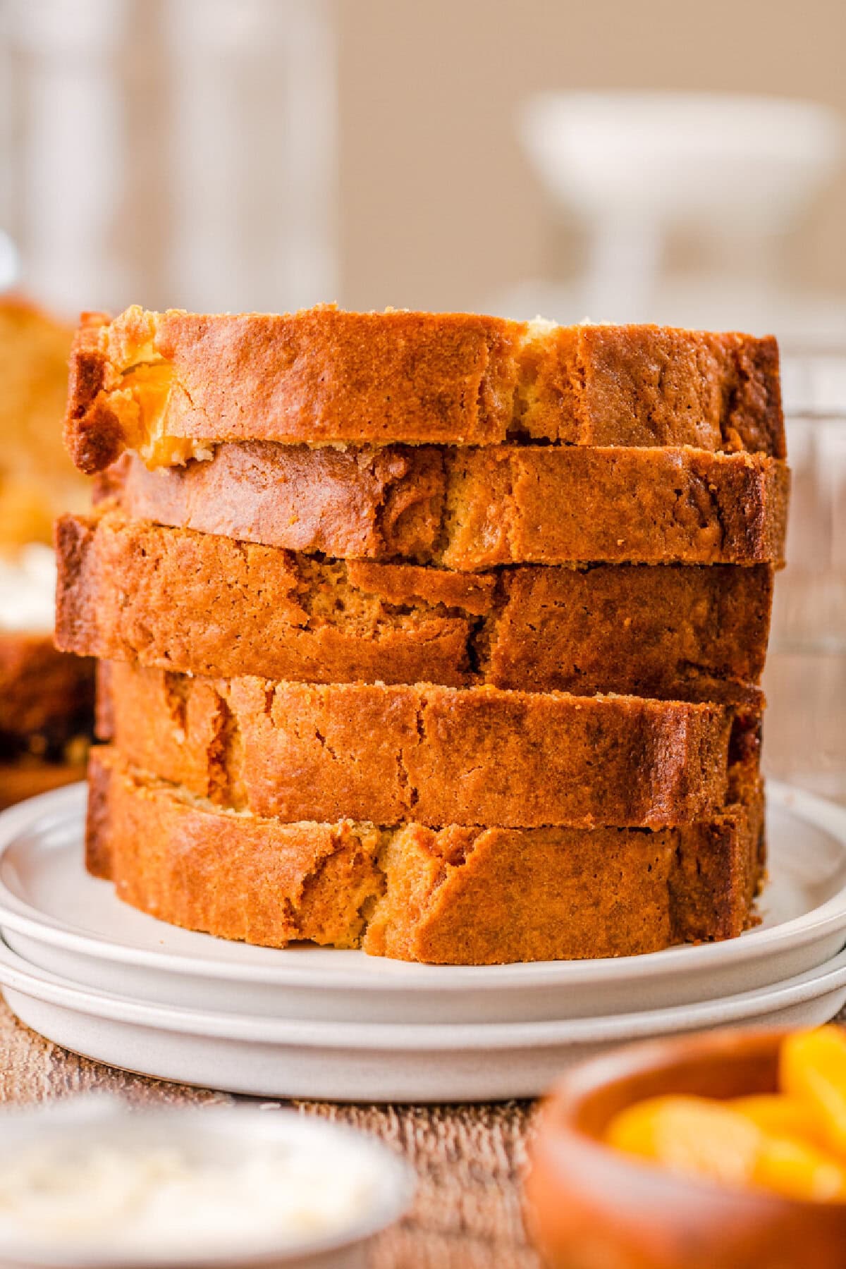 moist peach bread slices stacked on a white plate.