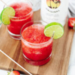 A fruity blended alcohol drink in a glass with a lime wedge.