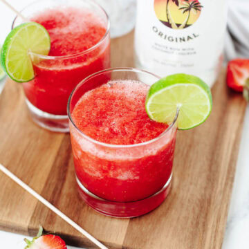 A fruity blended alcohol drink in a glass with a lime wedge.