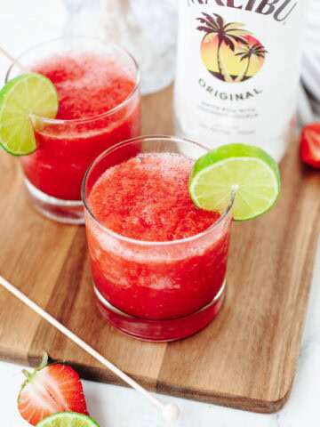 A fruity blended alcohol drink in a glass with a lime wedge.