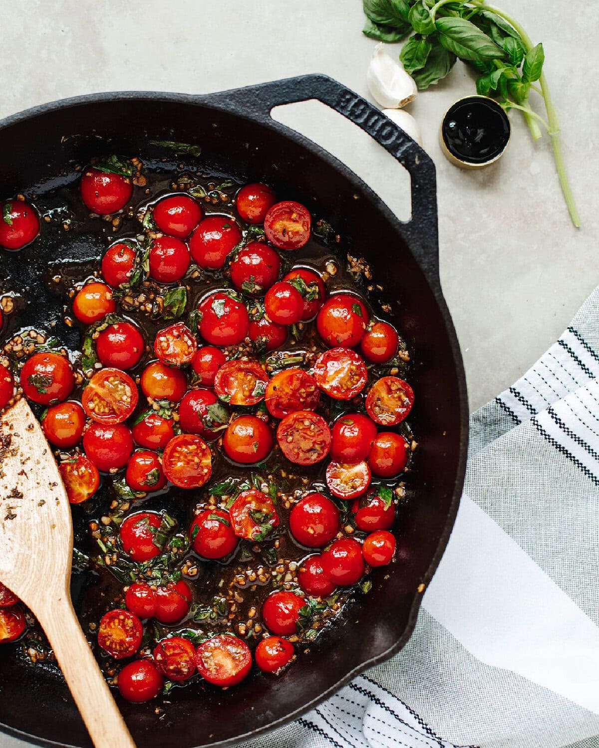 Cherry tomatoes, Basil, and olive oil cooking in a cast iron skillet.
