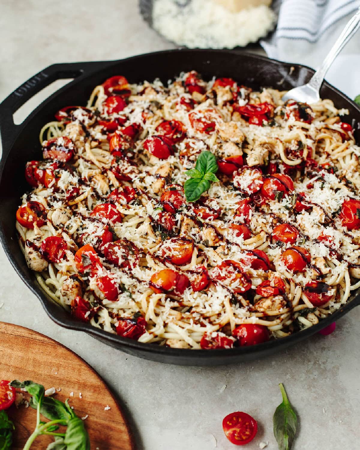 Bruschetta chicken pasta in a skillet with a balsamic glaze and Parmesan cheese on top.
