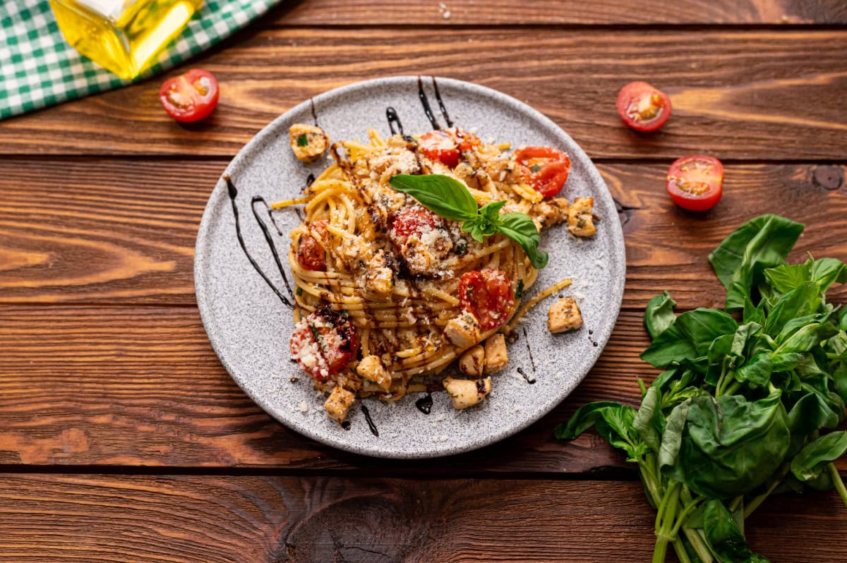 A serving of tomato basil pasta with chicken on a plate.