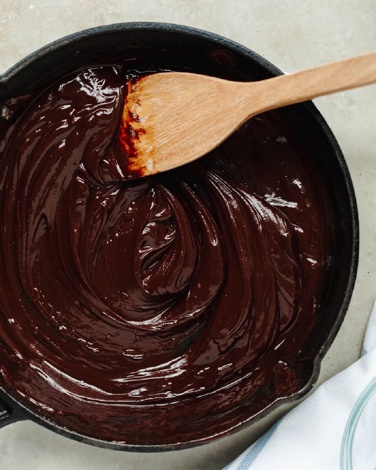 Chocolate chips melted into a heavy cream butter mixture using a wood spoon.