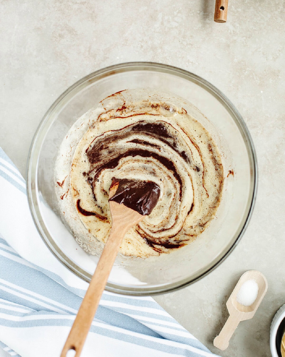 Melted chocolate combined with sugar and eggs in a glass mixing bowl.