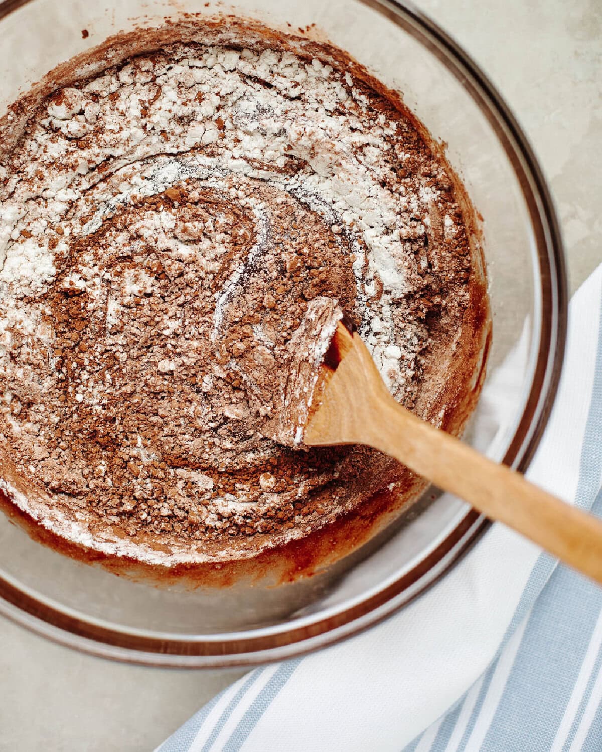Flour, cocoa powder, and salt combined with a chocolate mixture in a glass mixing bowl.