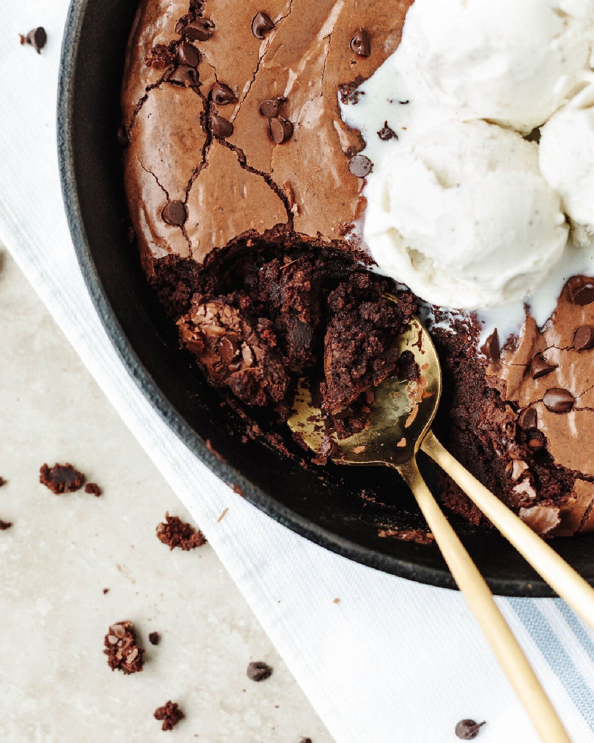 A spoon scooping brownies out of a cast iron skillet.