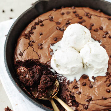 Baked brownies in a cast iron skillet with vanilla ice cream on top.