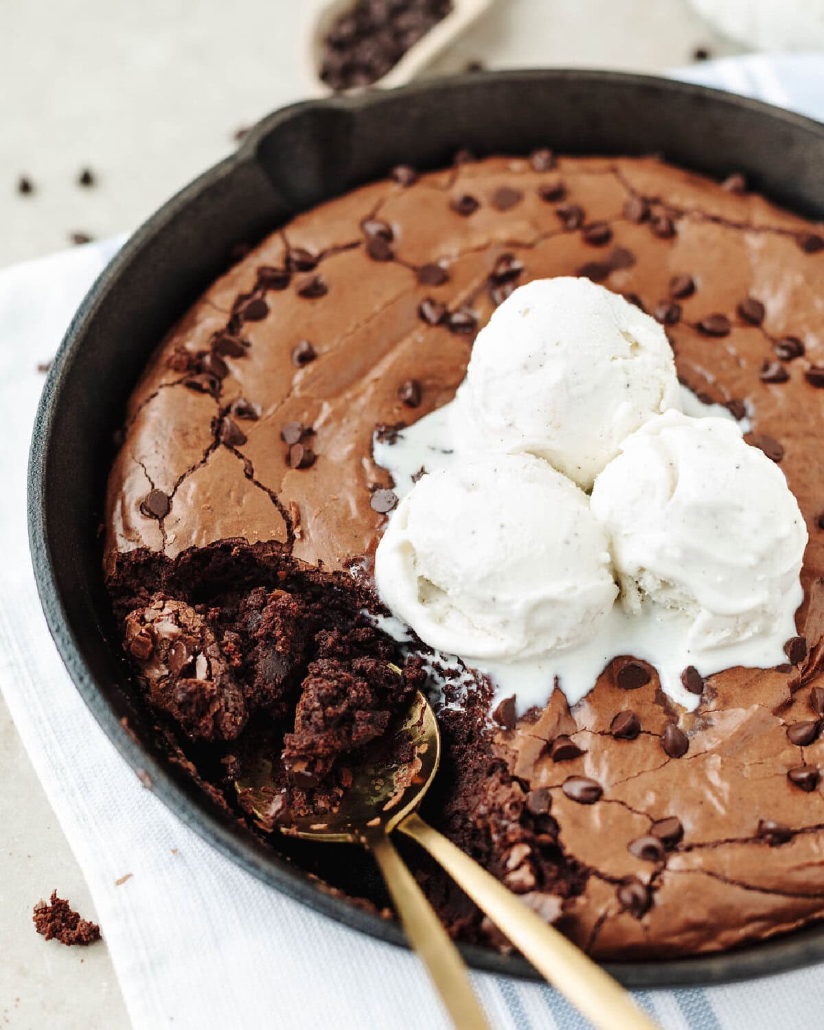 Baked brownies in a cast iron skillet with vanilla ice cream on top.